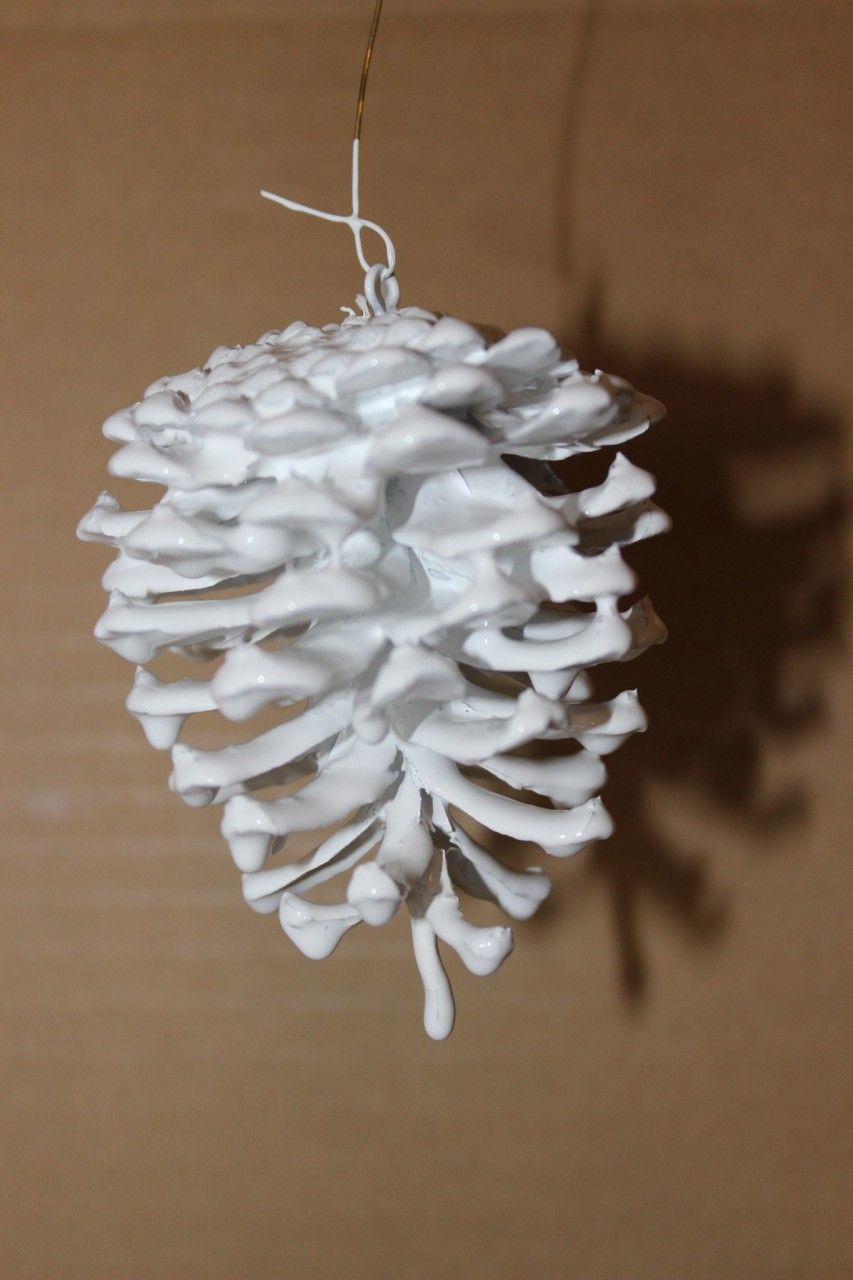 White pinecone with fresh paint dripping off it.