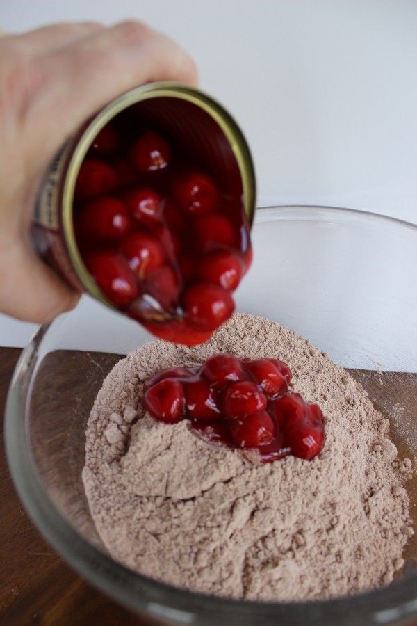 Adding canned cherries to the chocolate cake mix. \