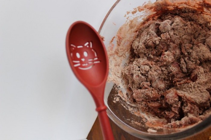 chocolate cherry muffins being mixed with red spoon