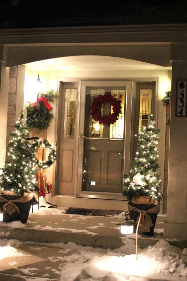 Christmas trees with white lights in planters and green swags under outdoor lights