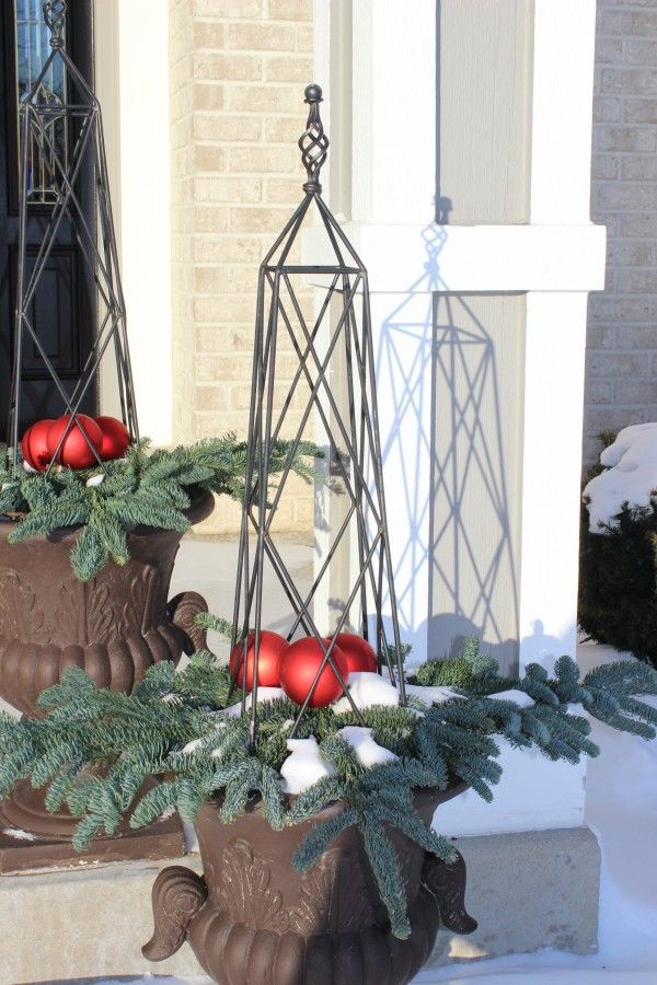 A christmas planter with pine branches and red ornaments.