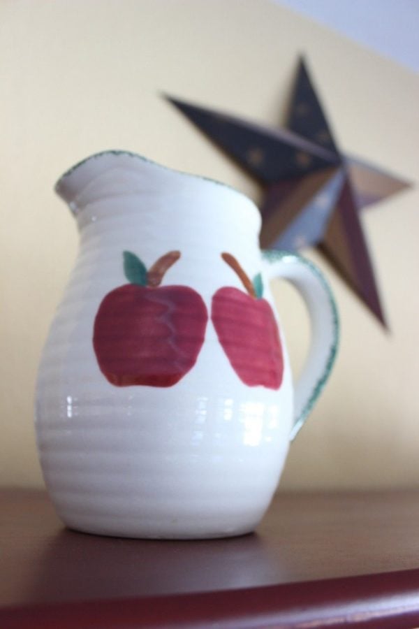 a white pitcher with big red apples that will be spray painted white.