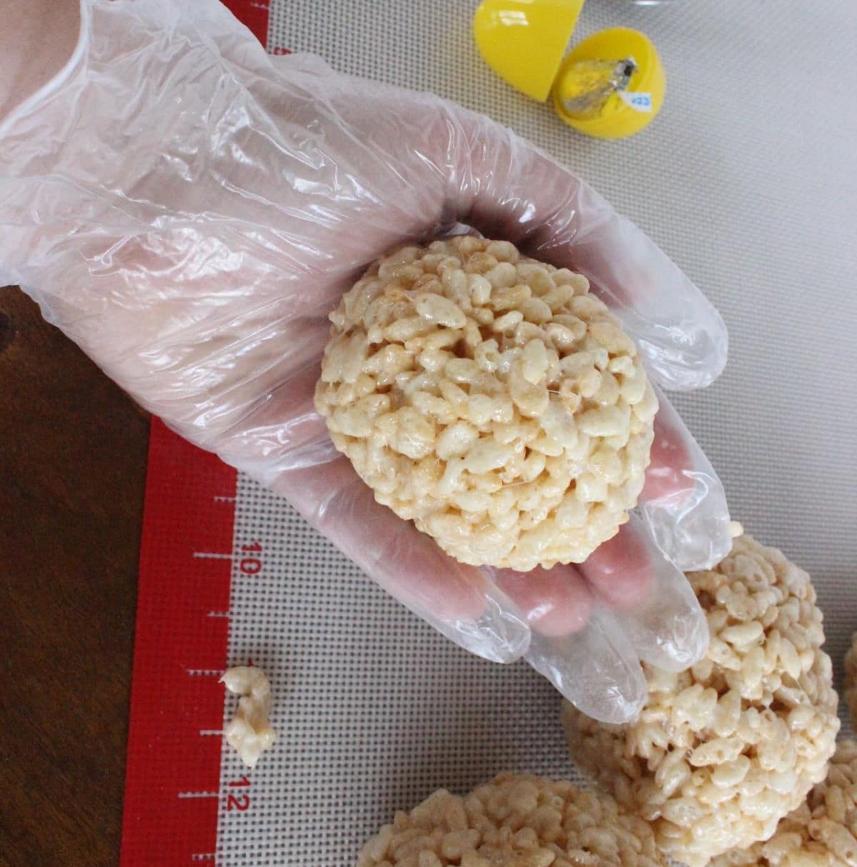 rice krispie egg formed around plastic egg held by gloved hand