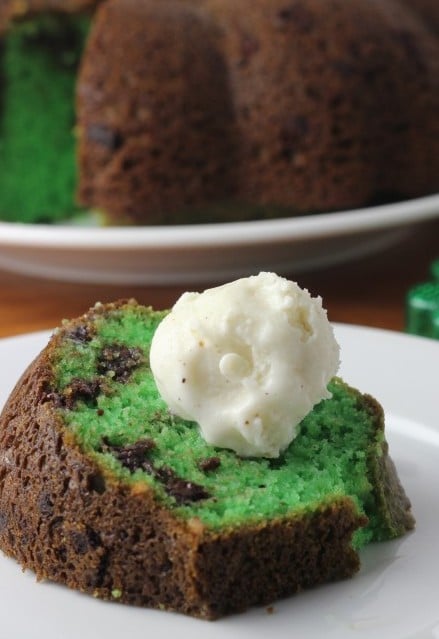 A piece of green pistachio bundt cake with a scoop of ice cream.