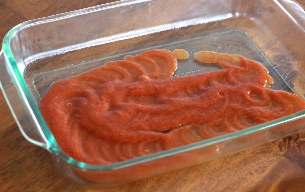 a casserole dish with tomato spread on the bottom