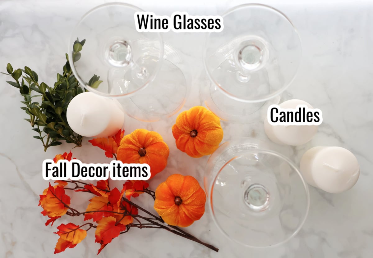 supplies to make fall wine glass centerpiece. Includes 3 candles, 3 wine glasses, small pumpkin to fit into wine glass, some faux small orange fall leaves and some green boxwood leaves