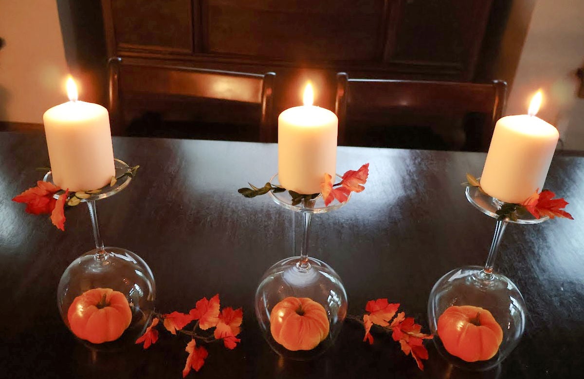 wineglass centerpiece using three upside down wineglasses, fall decor and a white candle on top.