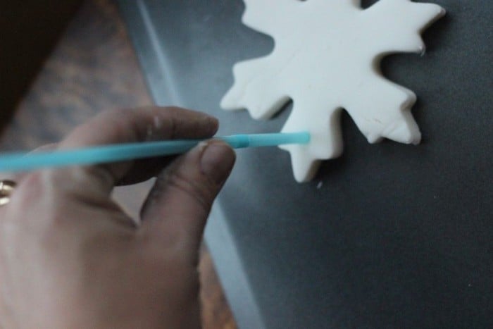 Using a straw to make a hole in the Christmas ornament