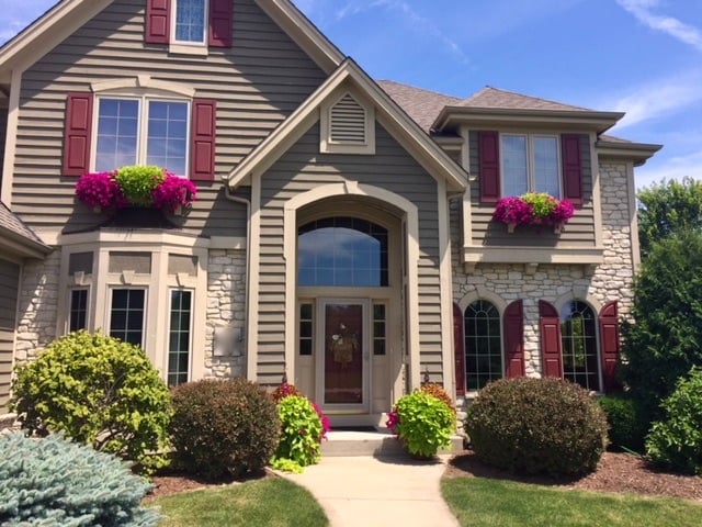 house with pink and green window boxes on each window.