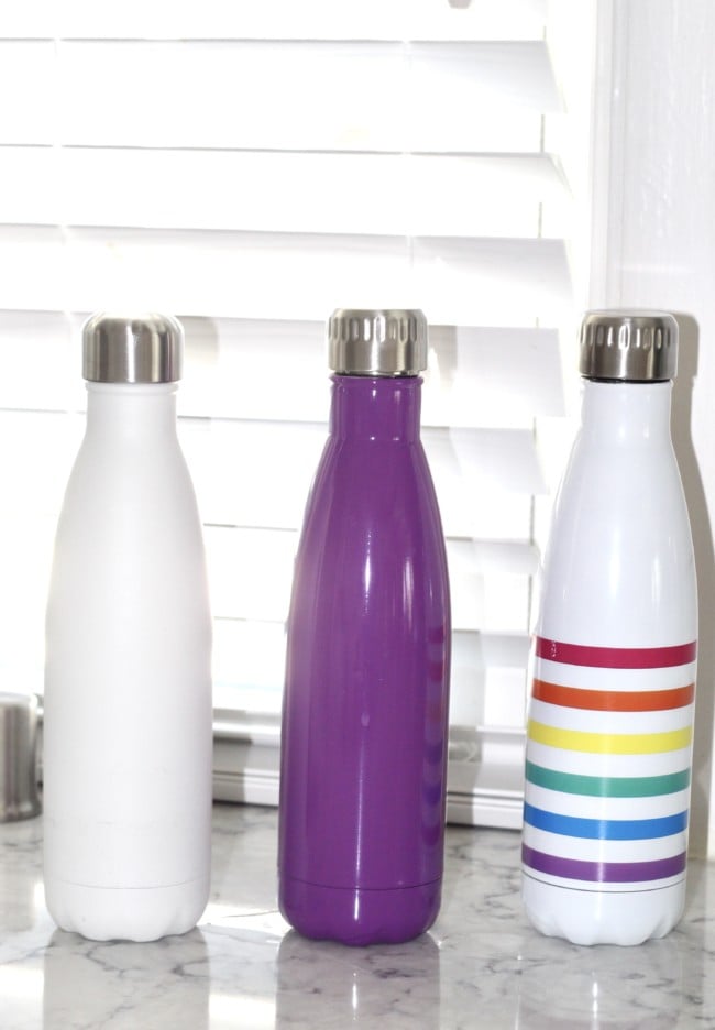 three similar shaped thermos' in different colors on the kitchen counter