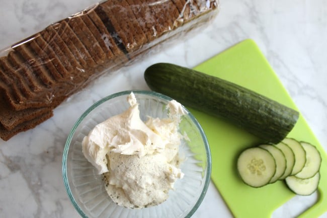 seasoned cream cheese in a bowl with english cucumber and bread in the background