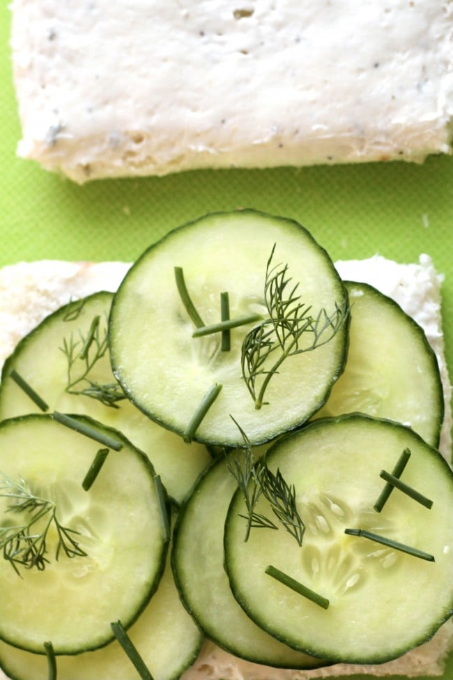 white bread with cucumber spread and sliced cucumbers on one piece of bread