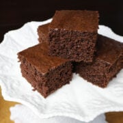 Three squares of brownie cake on a white plate.