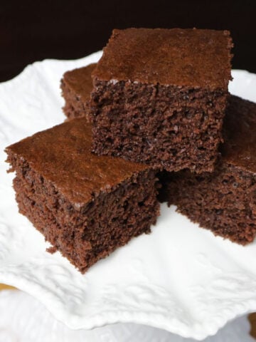 Three squares of brownie cake on a white plate.