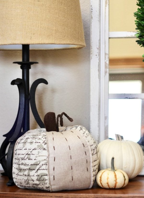 fabric pumpkin with white pumpkins sitting in front of a white chippy mirror.