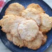 A pile of potato chip cookies o a blue plate, dusted with powdered sugar