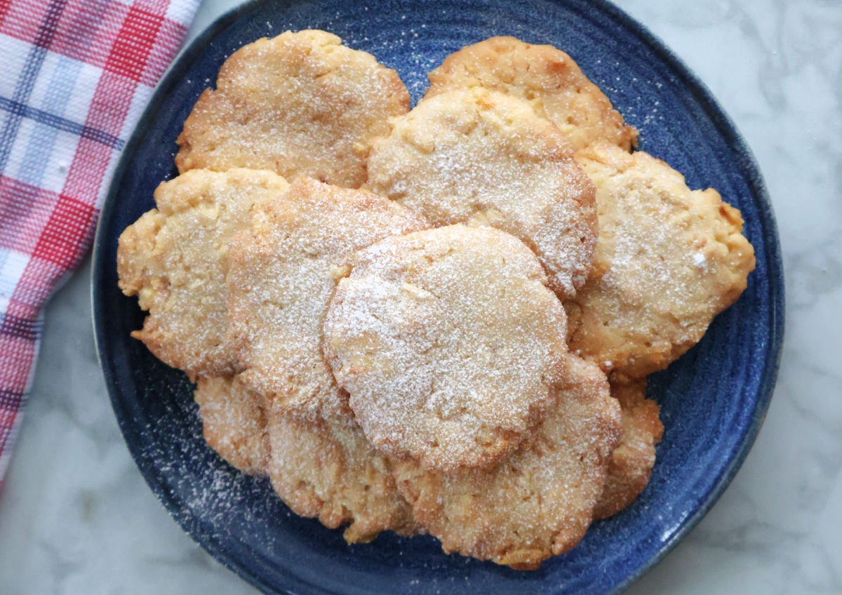 A pile of potato chip cookies o a blue plate, dusted with powdered sugar