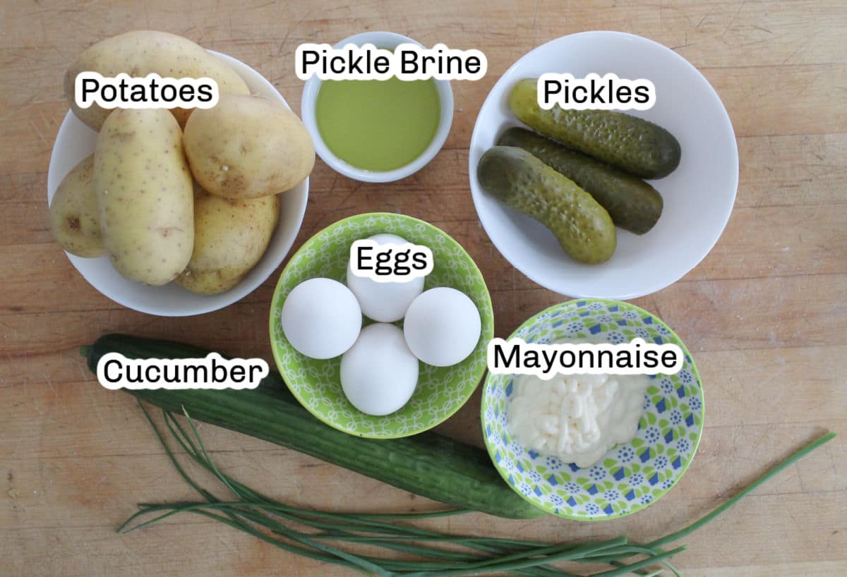 Potato salad ingredients including potatos, pickles, pickle brine, eggs, cucumber and mayonnaise.