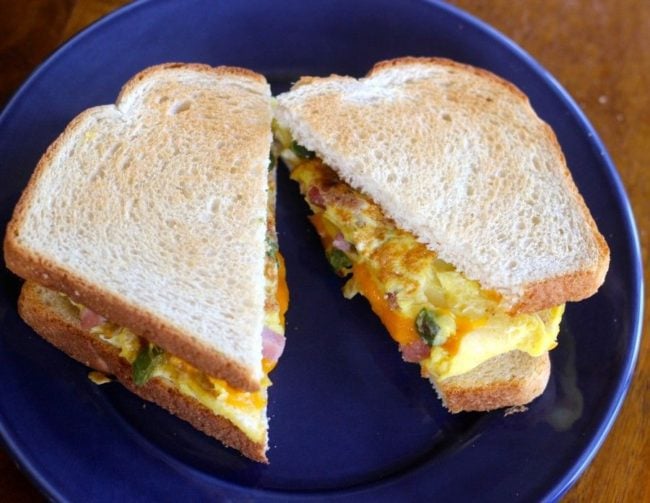 Western Sandwich with scrambled eggs and additional ingredients peeking out from toasted bread.