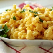 a plate of mac and cheese with a sprinkling of green basil.