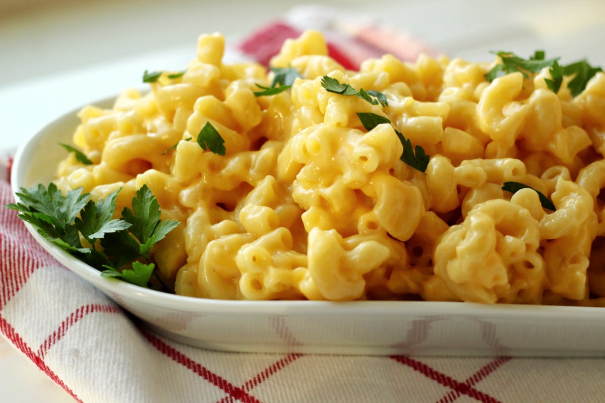 a plate of mac and cheese with a sprinkling of green basil.