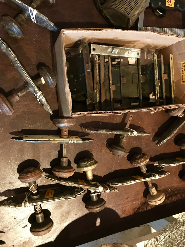 A table full of old doorknobs and old mortise locks.