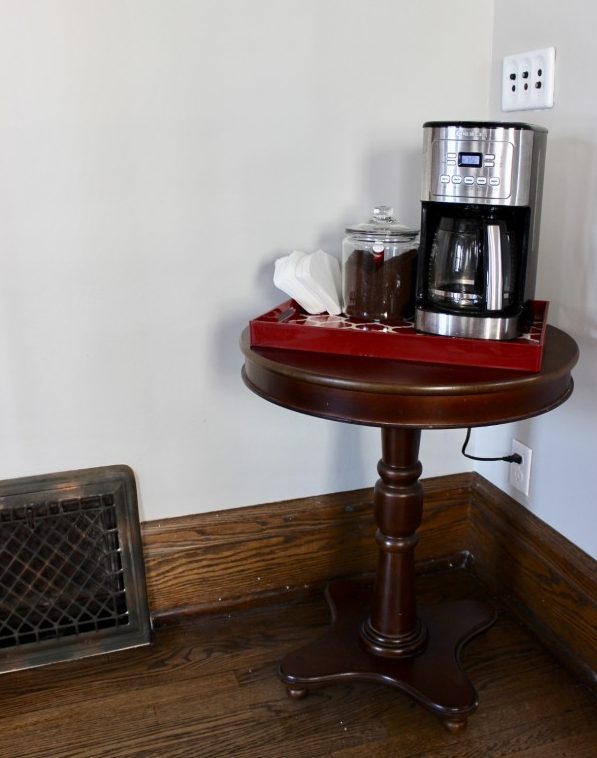 Original coffee station with the coffee maker on a red tray on an end table.