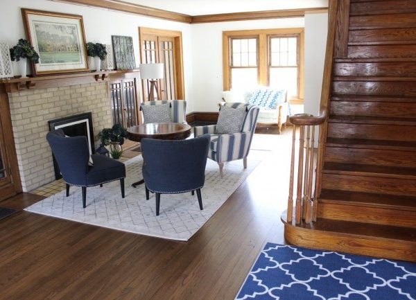 Blue living room accent chairs around a vintage wooden table in front of the original 1920's fireplace.