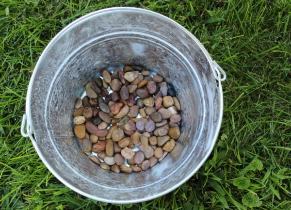 galvanized pail with a layer of stones