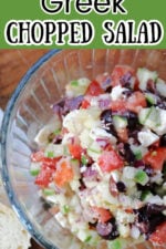 Greek chopped salad with chopped tomatoes, cucumbers, red onions, olives, and feta in a clear bowl.