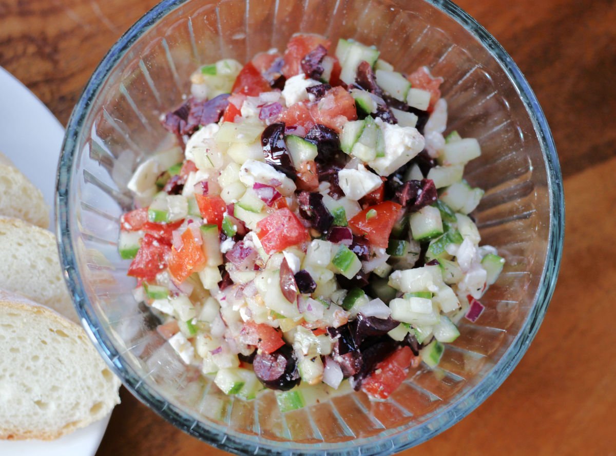 Chopped veggies, olives and feta in a bowl topped with feta and simple dressing.