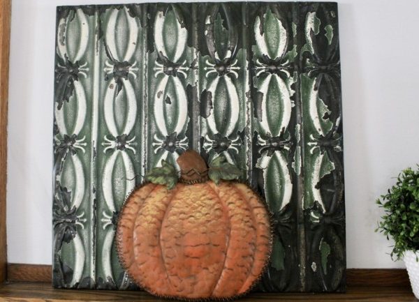 orange metal pumpkin in front of green tin ceiling tile