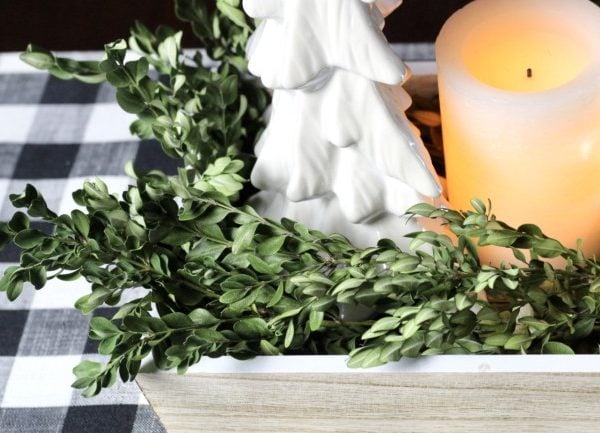 white ceramic Christmas tree on a bed of dried boxwood leaves.