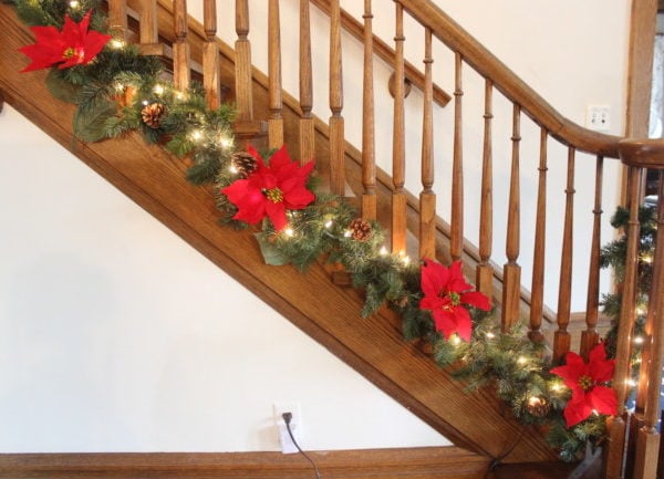 green garland with red pointsettas at the base of the banister