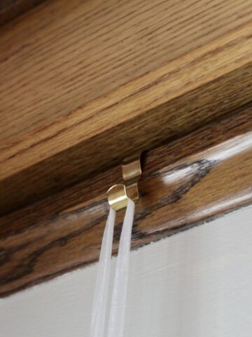 a picture rail hook attached to the picture rail molding with a ribbon attached to it.