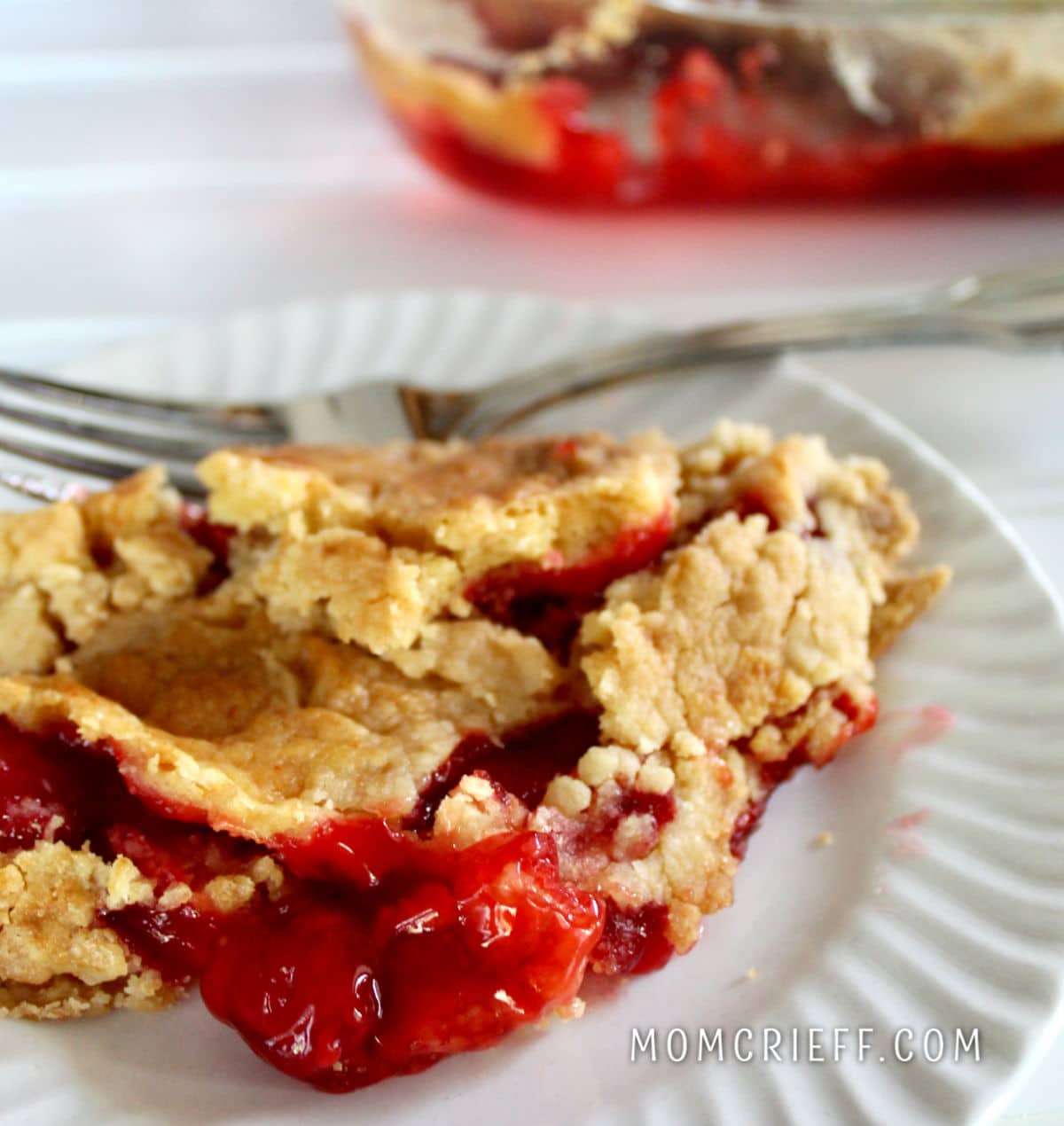 cherry cobbler with cherries spilling onto white plate