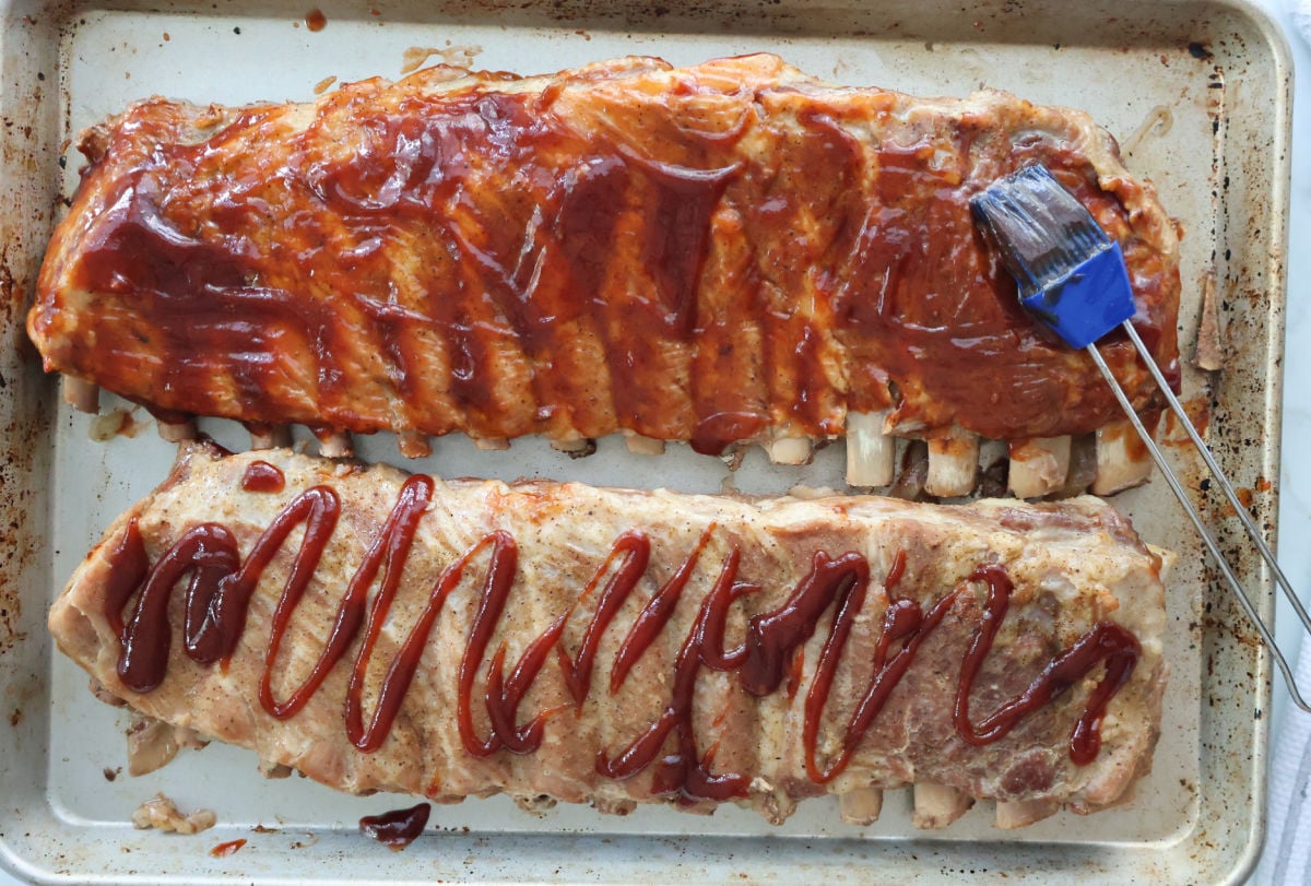 barbeque sauce being brushed onto roasted ribs.