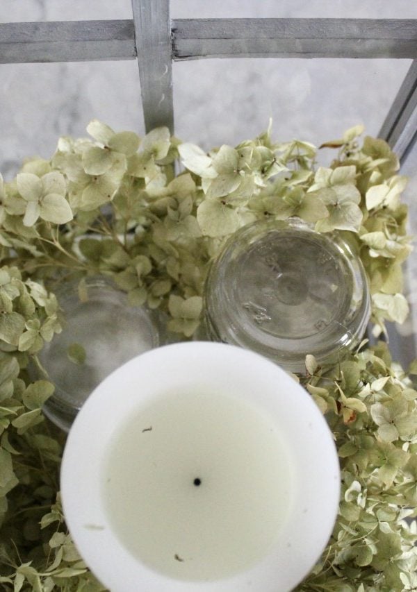 placing white candle on mason jar for height in a lantern