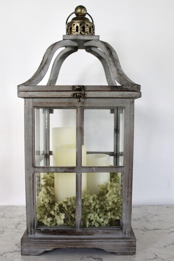 wood lantern with white candles and dried hydrangeas