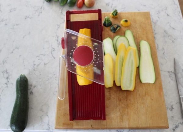 slicing yellow zucchini on a mandolin