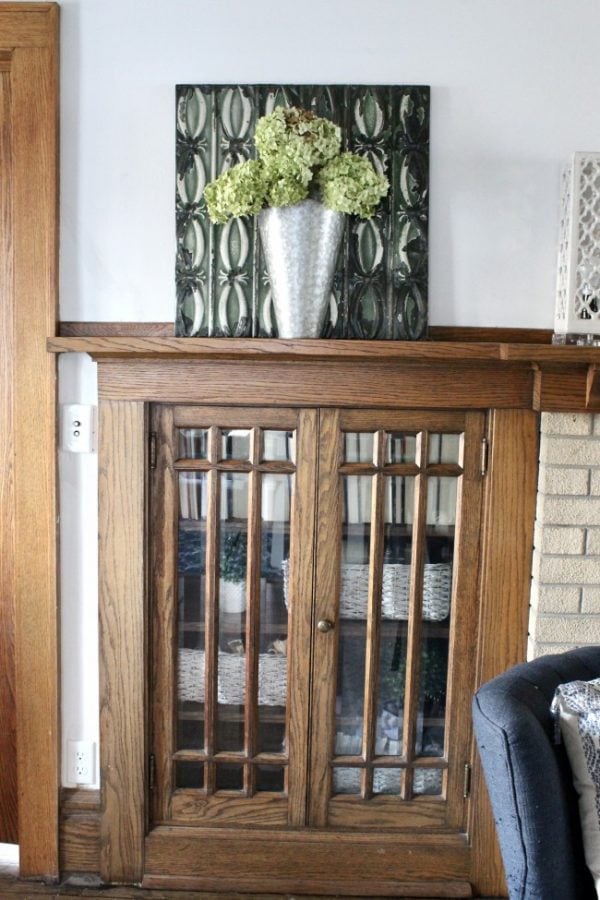 vintage built in with a display on top that included a large green ceiling tile, a galvanized steel vase with a dried hydrangea display.