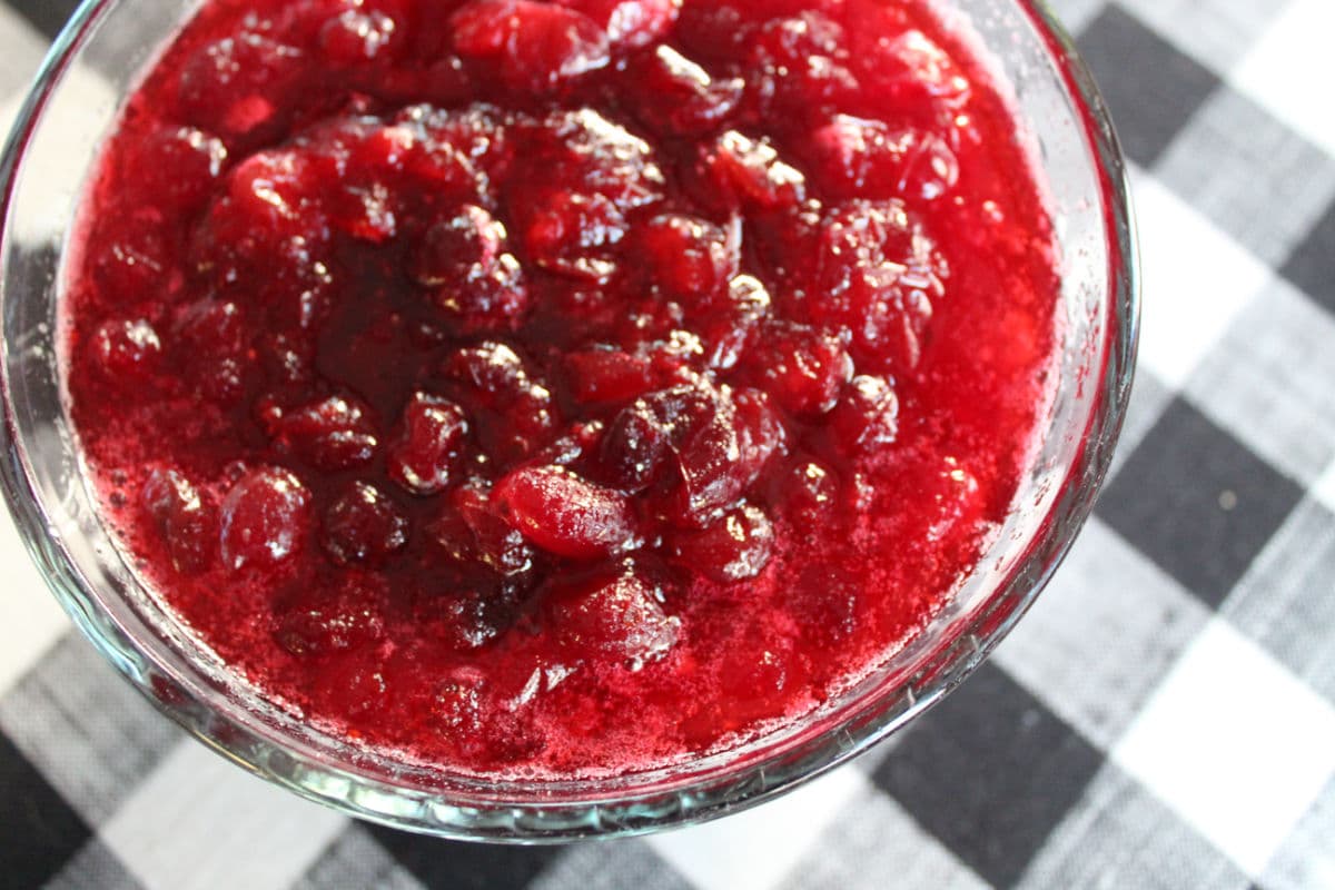 a bowl of cranberry sauce against a black and white checked tablecloth.