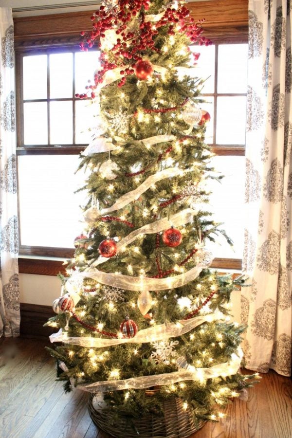 Christmas tree with white lights, silver ribbons in a christas tree collar basket