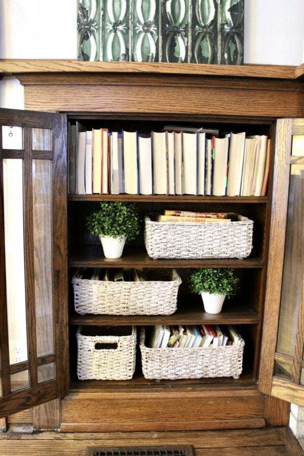 view of interior of built-in with books, and white painted wicker baskets
