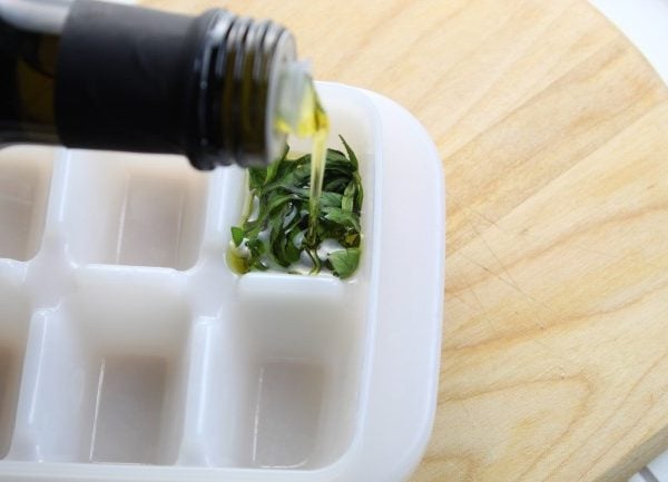 fresh basil in an ice cube tray with olive oil