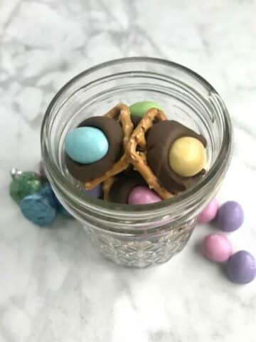 mason jar with pretzels with M&M's and Hershey kisses on them.