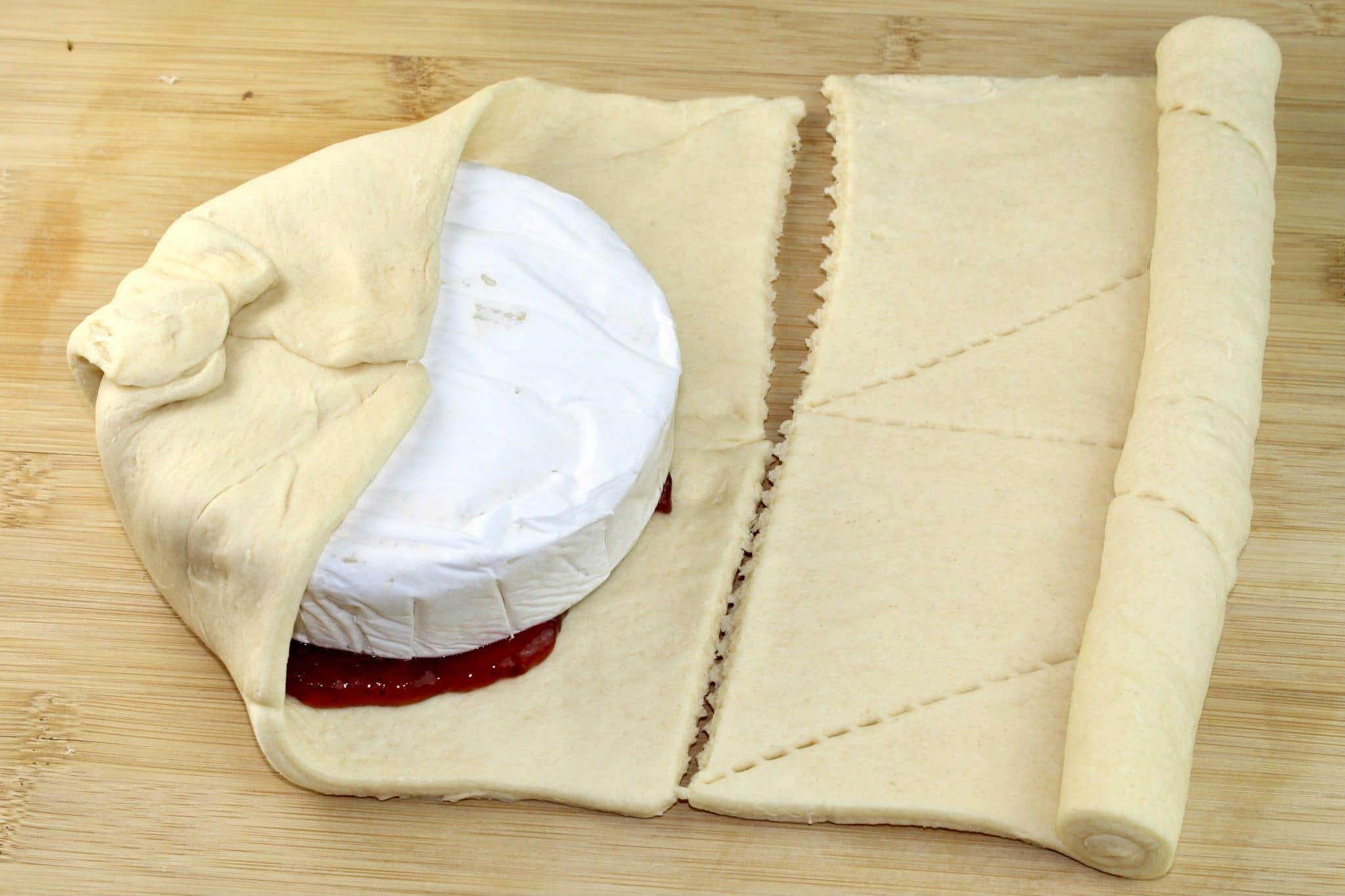 brie placed on preserves and dough is folded around it.