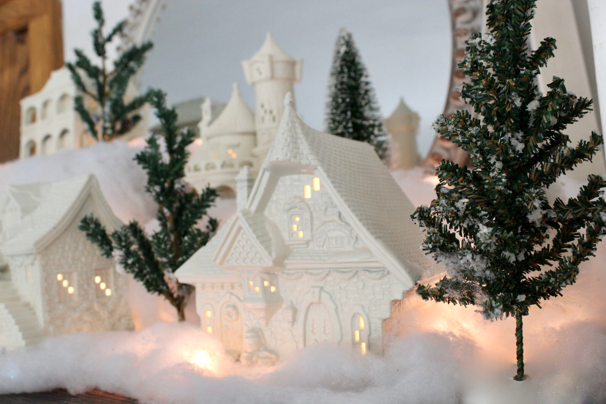 white Christmas village in front of a mirror.