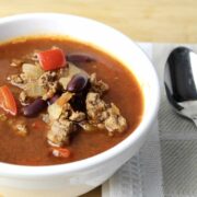 close up view of mexican soup showing ground beef, red peppers and kidney beans