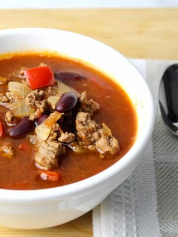 close up view of mexican soup showing ground beef, red peppers and kidney beans